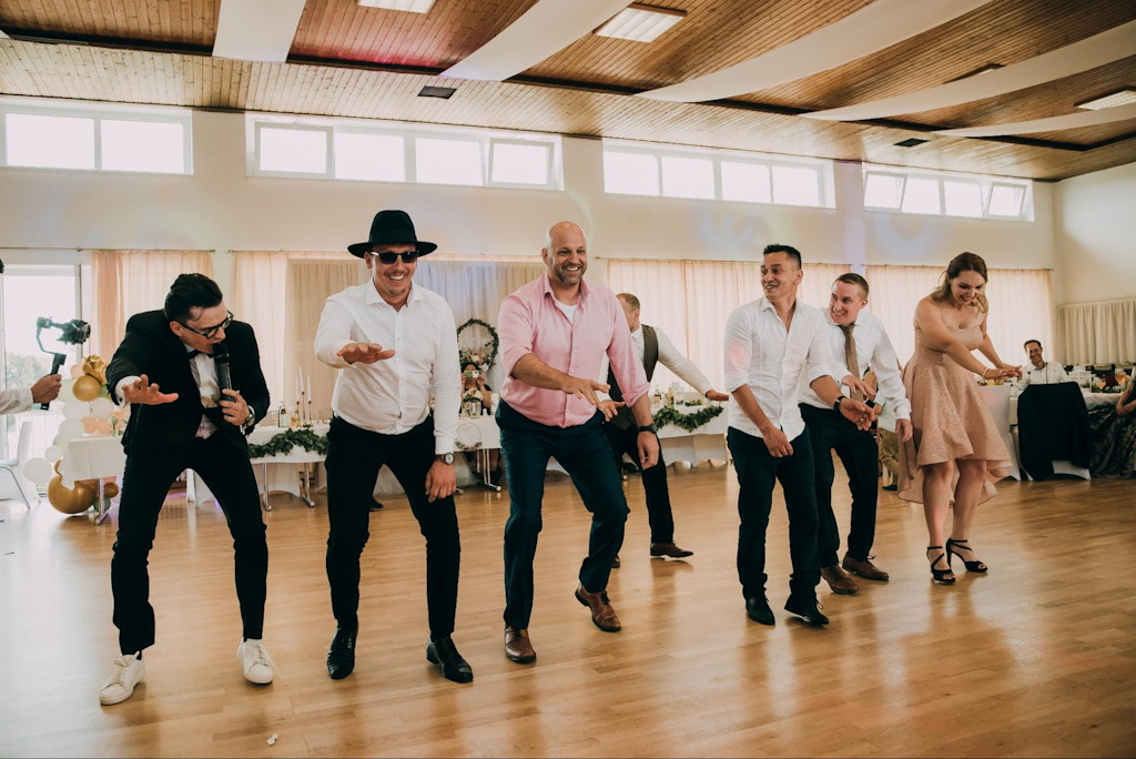 Hochzeitsmoderator und G&auml;ste tanzen gemeinsam in einer Reihe bei einem Spiel auf der Tanzfl&auml;che